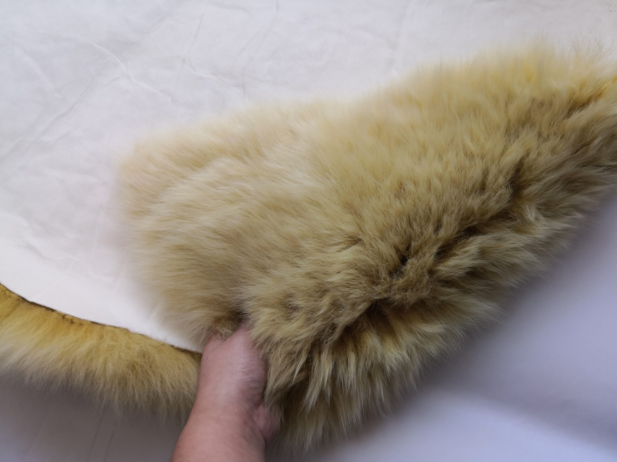 A hand lifted the edge of the sheepskin rug to reveal the soft wool.