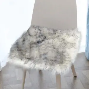 A white color with gray tip sheepskin cushion sits on the chair.